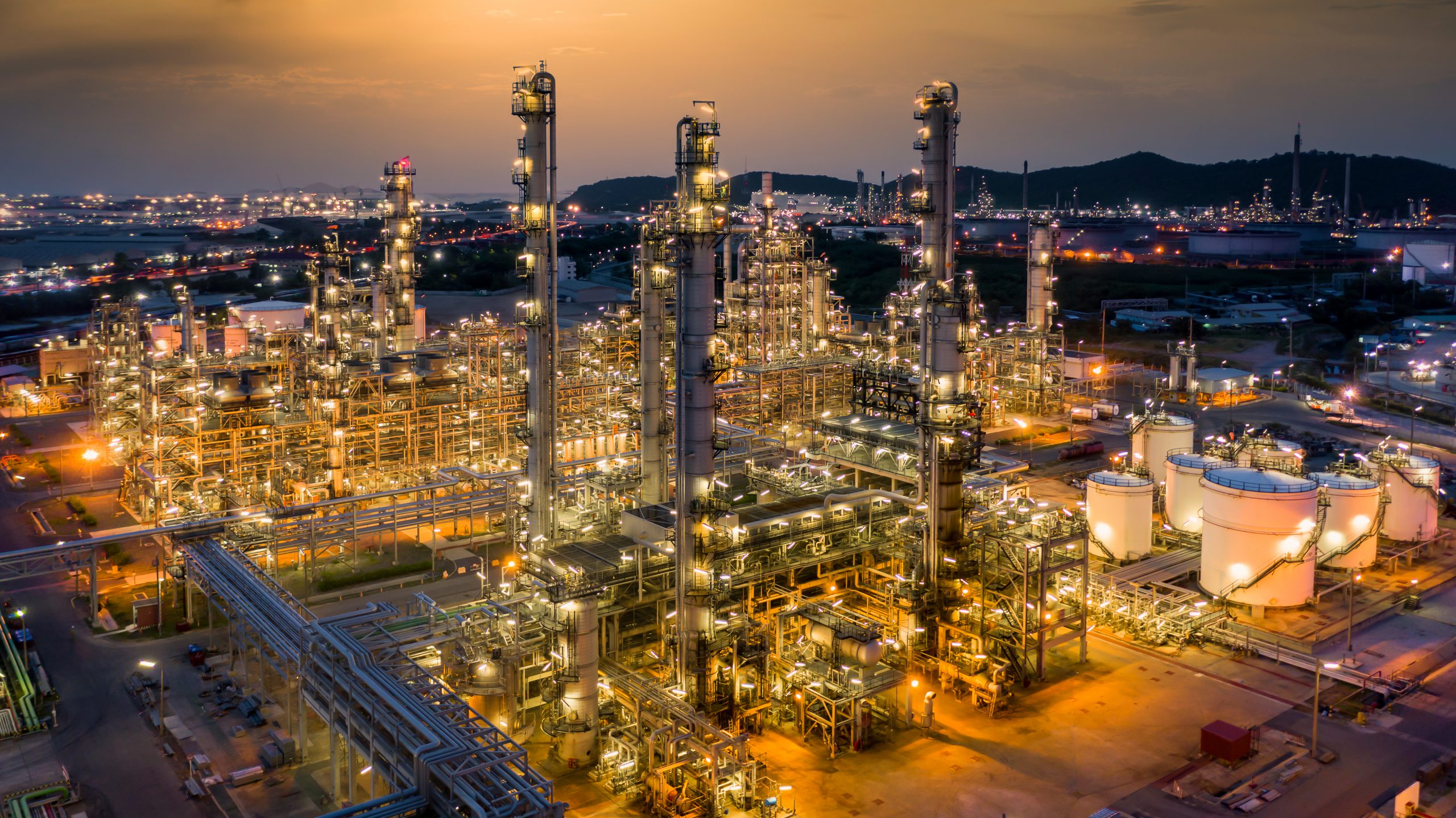 Aerial view of oil refinery plant at dusk illuminated by yellow lights